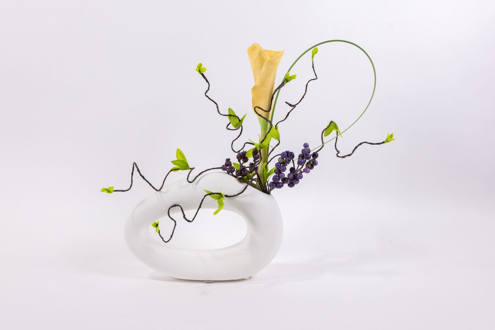 White Oval Vase With Yellow Blossom Purple Berries And Grass Blade